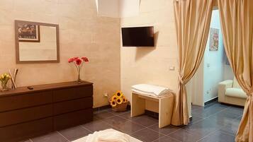 Un baño moderno con tocador de madera, televisor de pantalla plana, un taburete pequeño y un perchero para toallas.