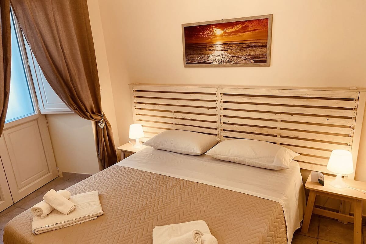 A neatly made bed with a wooden headboard, two pillows, and two bedside lamps.