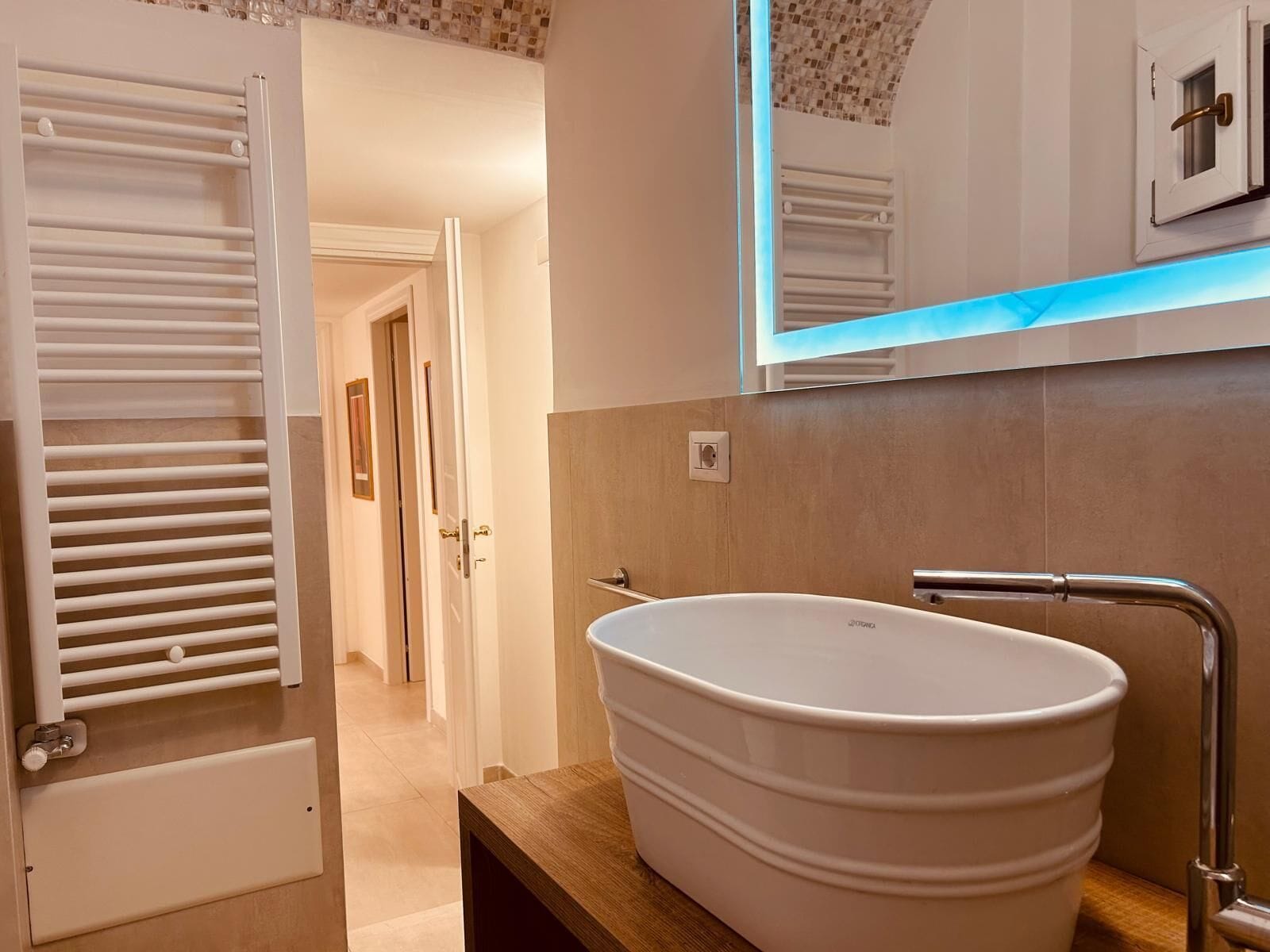 Un baño moderno con una bañera independiente, un espejo y un perchero para toallas.