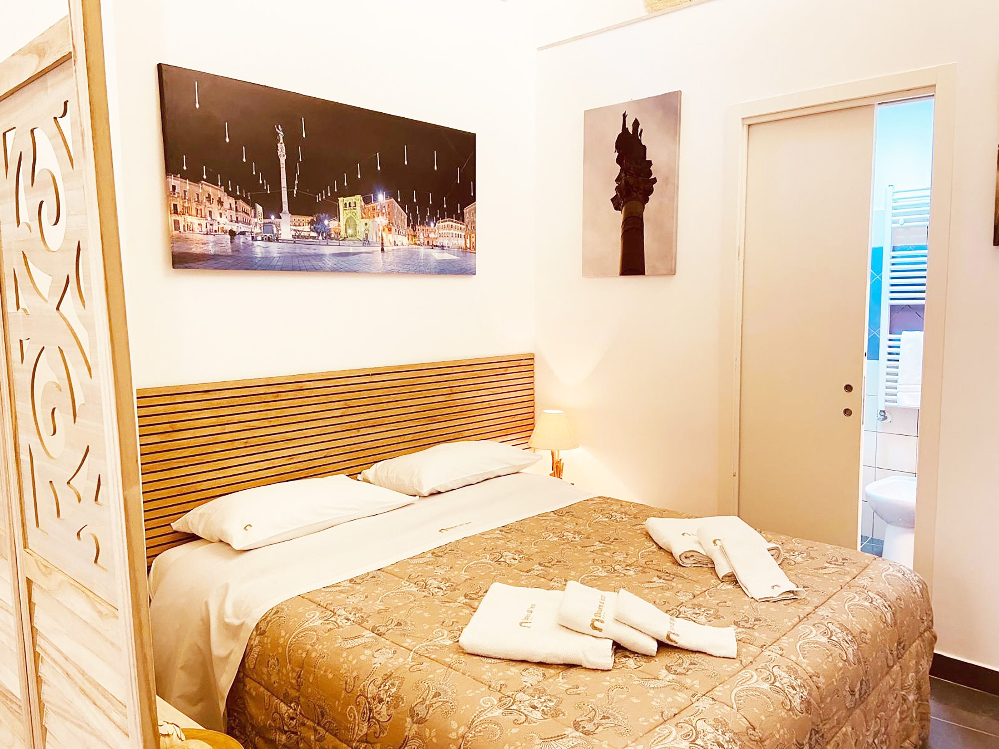 A hotel room with a bed, a night view painting, a statue, and a door leading to a balcony.