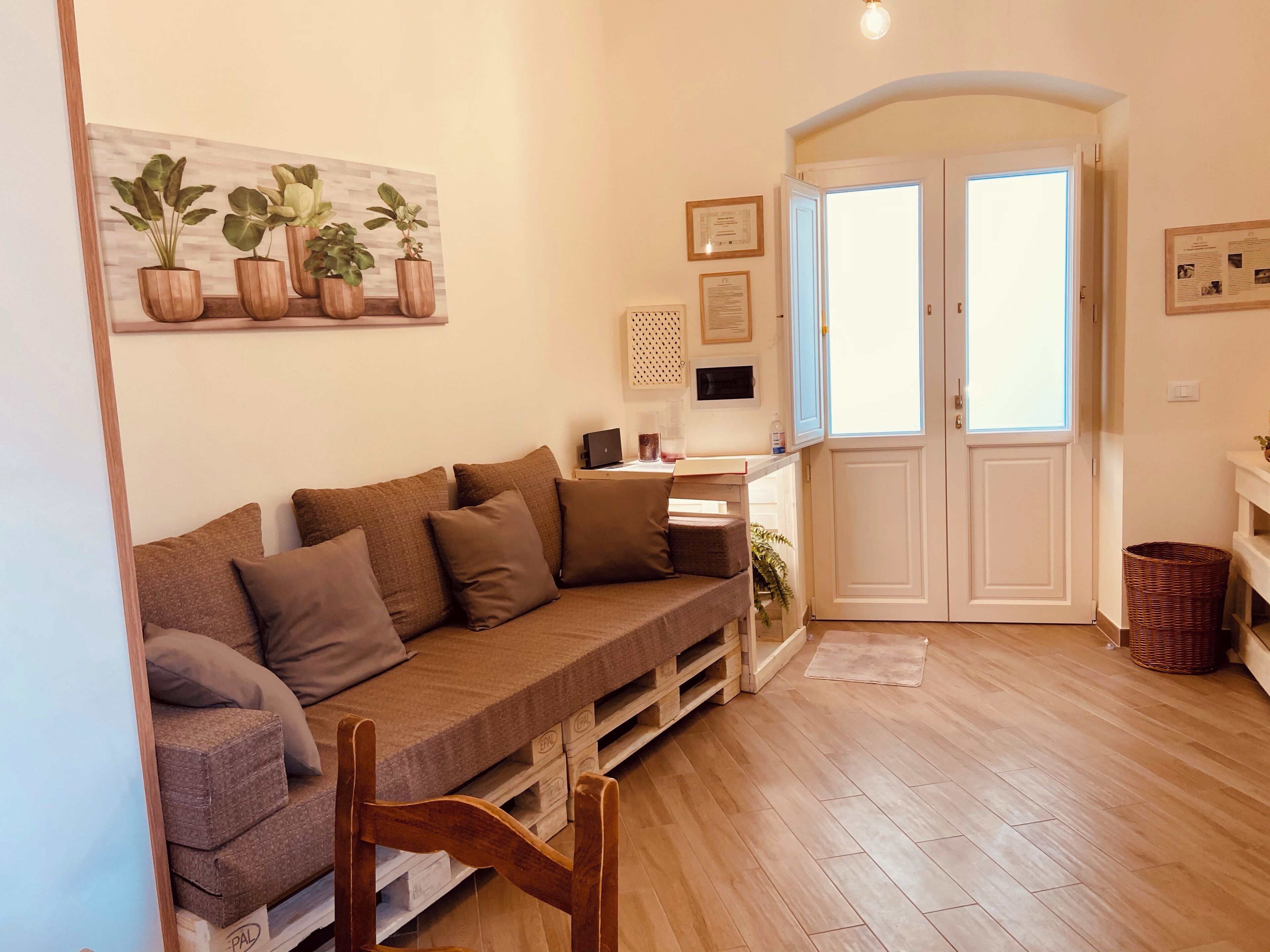 A cozy living room with a sofa, wooden floor, and a door leading to another room.