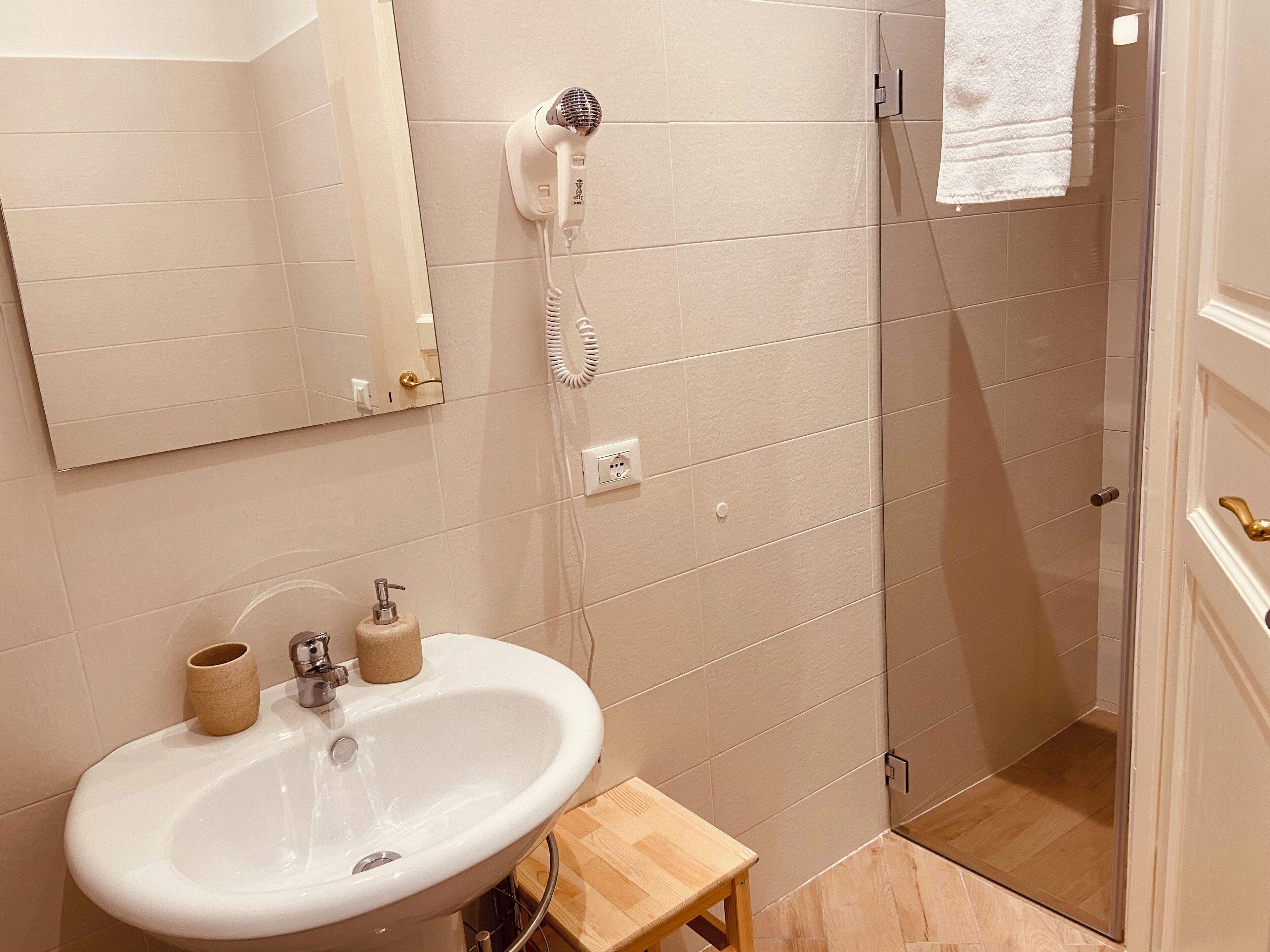 Casa de banho com lavatório, espelho, secador de cabelo e porta-toalhas.