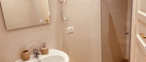 Baño con lavamanos, espejo, secador de pelo y toallero.