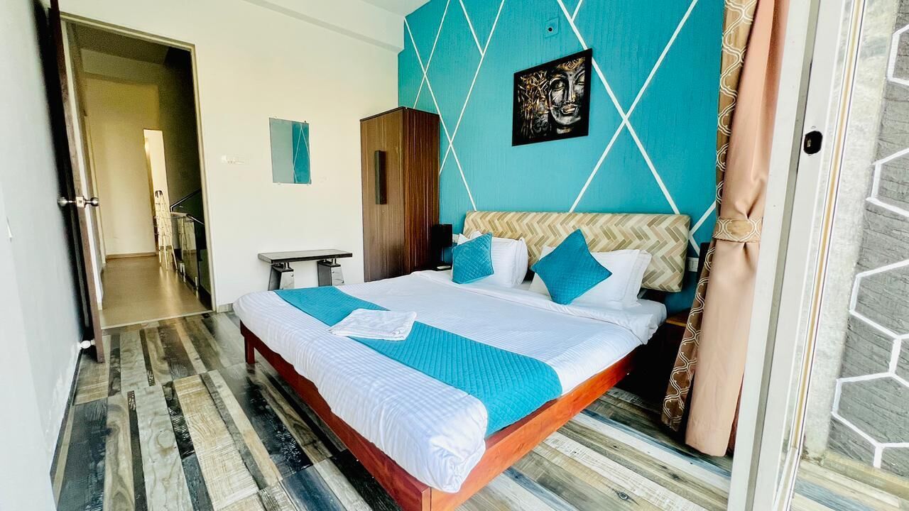 A hotel room with a bed, a wardrobe, a desk, and a bathroom visible in the background.