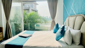 A bed with a blue and white bedspread, a beige headboard, and blue pillows. - Ashford 4 BHK With Pvt Pool By Stellar Stays (Mawal)
