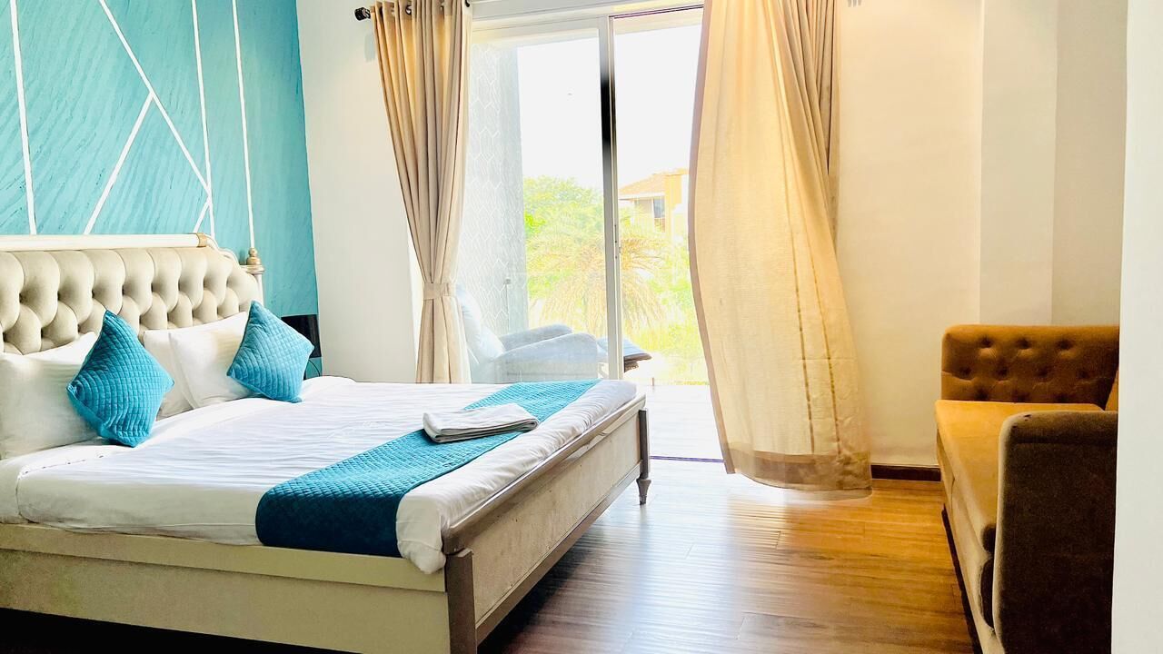 A bedroom with a bed, a chair, and a view of the outdoors.