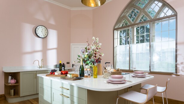 A kitchen with a large island, a clock on the wall, and a window with a view of trees. - Bryngwilla Gate Lodge - Oswestry , Shropshire (Oswestry)