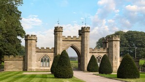 A castle entrance with a gravel path, a large archway, and symmetrical towers. - Bryngwilla Gate Lodge - Oswestry , Shropshire (Oswestry)