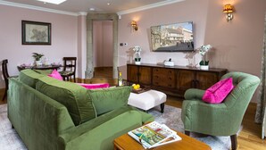 A living room with a green sofa, a green armchair, a wooden coffee table, and a dining area with a table and chairs. - Bryngwilla Gate Lodge - Oswestry , Shropshire (Oswestry)