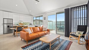 A modern apartment with a kitchen, dining area, living room, and balcony. - White Beach - Whole Property (Terrigal)