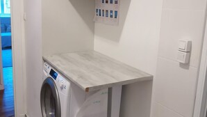 Een wasruimte met een wasmachine, een droogrek en een bedieningspaneel.
