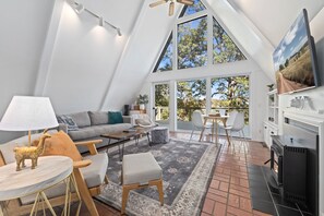 Ein stilvolles Loft-Wohnzimmer mit hoher Decke, großen Fenstern, Kamin und Essbereich.