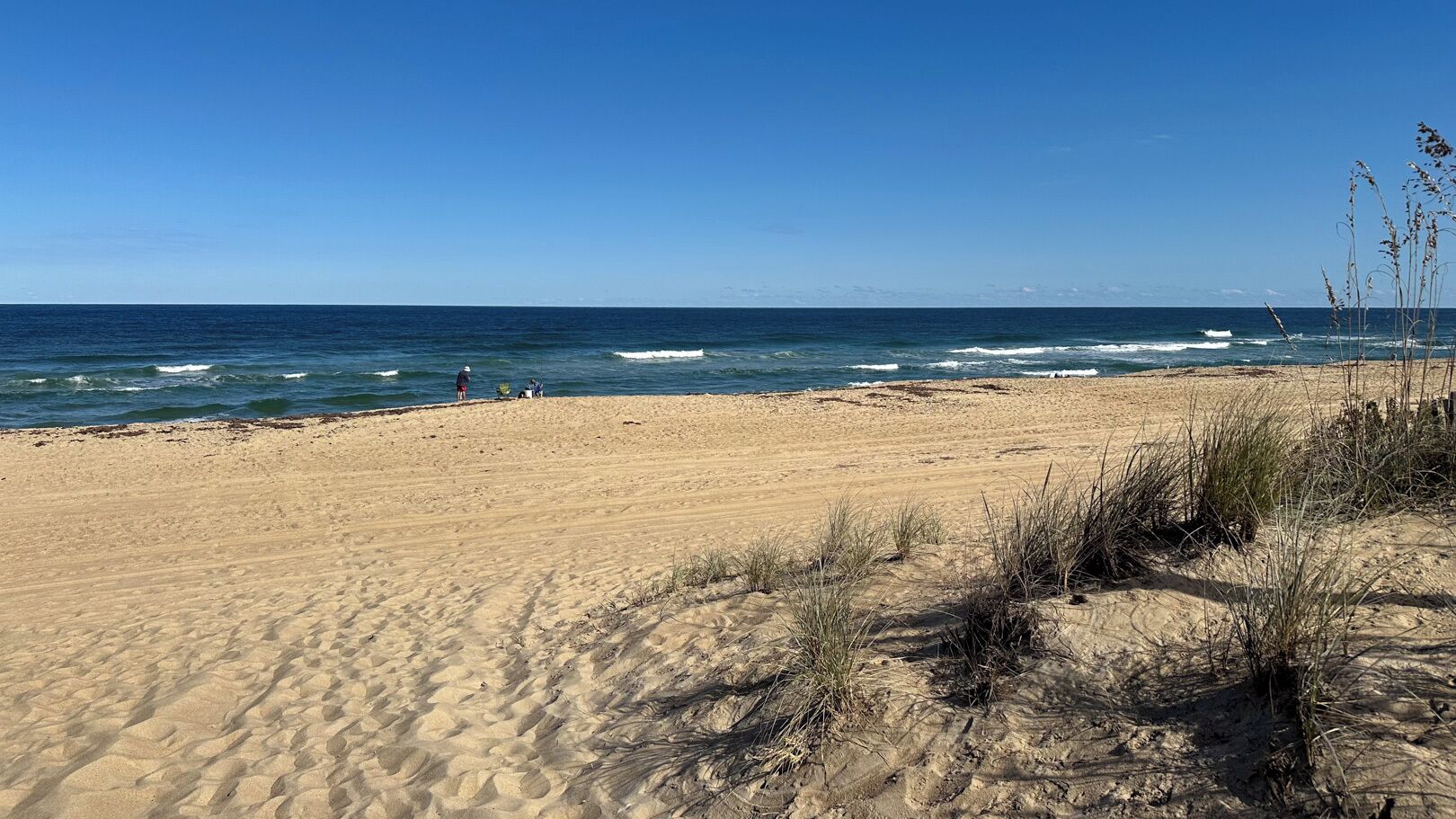 A sandy beach with gentle waves and a clear blue sky.