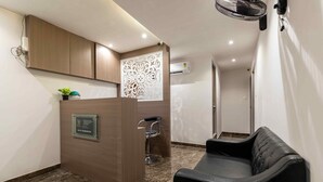 A reception area with a wooden desk, a black leather chair, and a decorative wall panel. - HOTEL METROMAX (Mumbai)