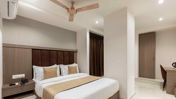 A modern hotel room with a large bed, a desk, and a ceiling fan. - HOTEL METROMAX (Mumbai)