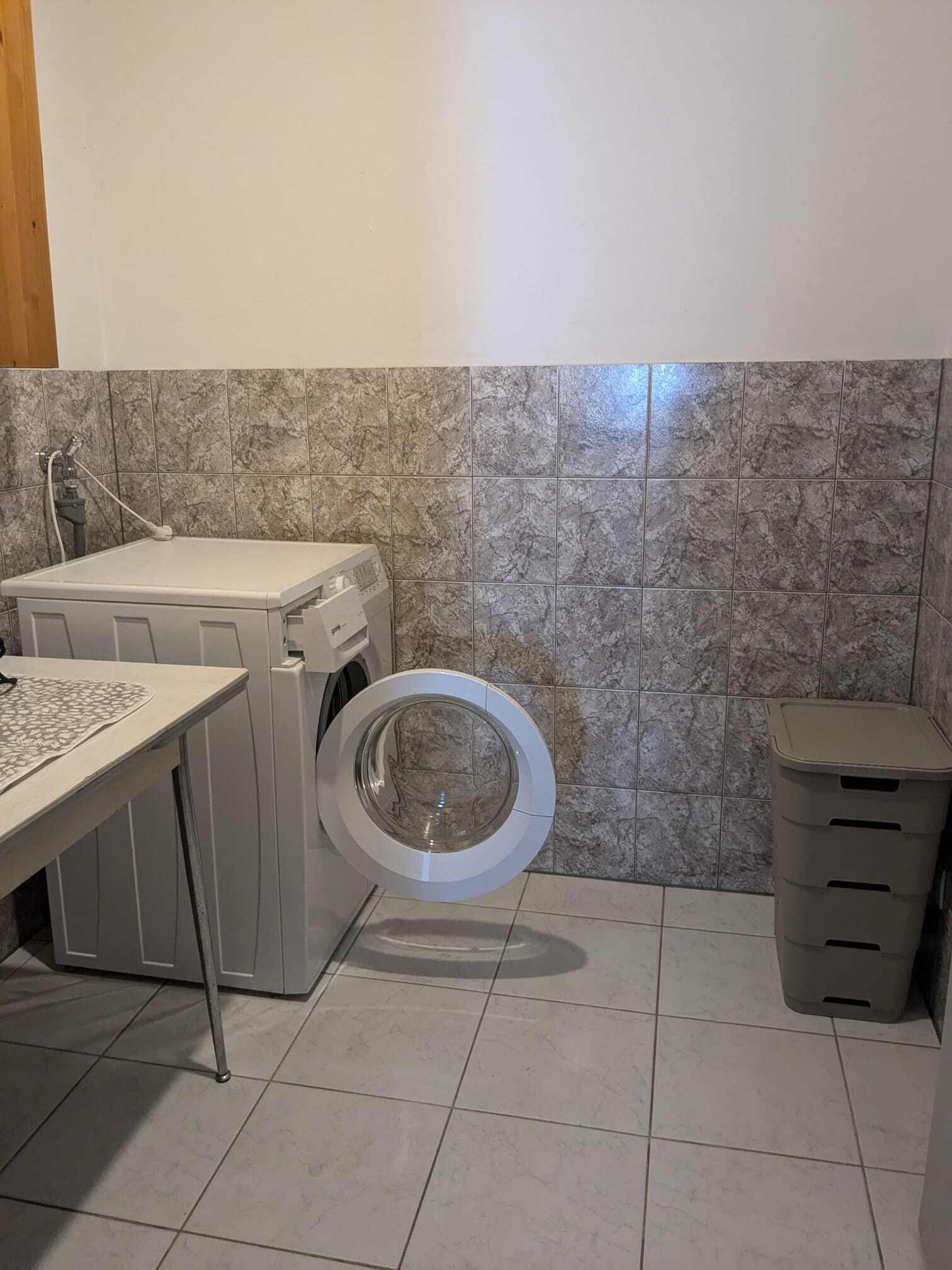 Une petite buanderie équipée d’un lave-linge, d’un sèche-linge et d’une poubelle.