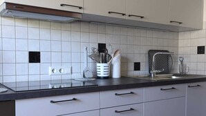 Une cuisine moderne avec des armoires blanches, un comptoir noir et un sol à carreaux.