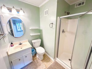 A bathroom with a toilet, sink, mirror, shower, and a towel rack.