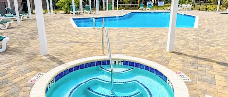 A swimming pool with a 3 FT depth marker, surrounded by a brick deck and white lounge chairs.