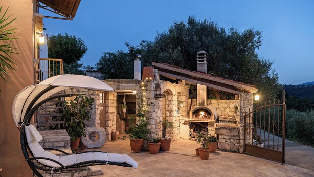 A stone building with a fireplace, outdoor seating, and potted plants. - Kritiko Archontiko, Nature & Private Pool Escape

 (C6Q2+MP Aspro, Greece)