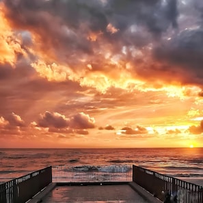A sunset view from a pier with a metal railing, overlooking the ocean. - Beachfront Apartment in Salerno (Salerno)