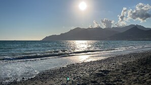 A beach with a rocky shoreline, waves, and mountains in the background. - SeaSide Apartment Salerno (Salerno)