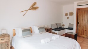 A bedroom with a bed, bedside tables, a window seat, and a wooden door.