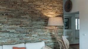 A living room with a stone wall, a white sofa, a wooden coffee table, and a floor lamp.
