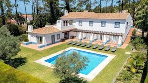 A large house with a swimming pool, multiple windows, and a covered outdoor seating area.
