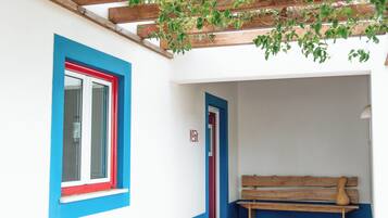 Un pasillo con un banco de madera, una puerta y un ventanal con detalles rojos.