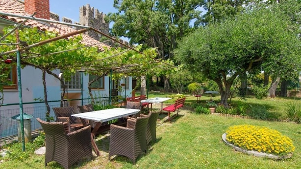 Ein Garten mit Tisch und Stühlen, einer Pergola und einem Blumenbeet.