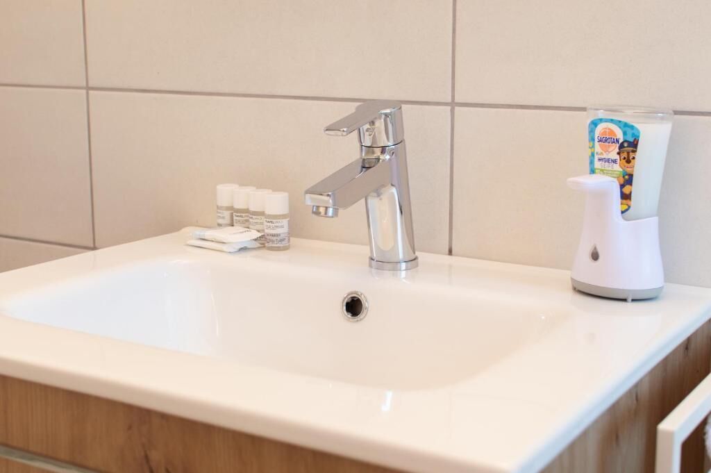 A bathroom sink with a modern faucet, a soap dispenser, and a hand soap bottle.