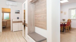 Ein modernes Zimmer mit einer Holzwand, einer Bank, einem Essbereich mit Tisch und Stühlen sowie einer Küchenzeile mit Schränken und einem Fenster.
