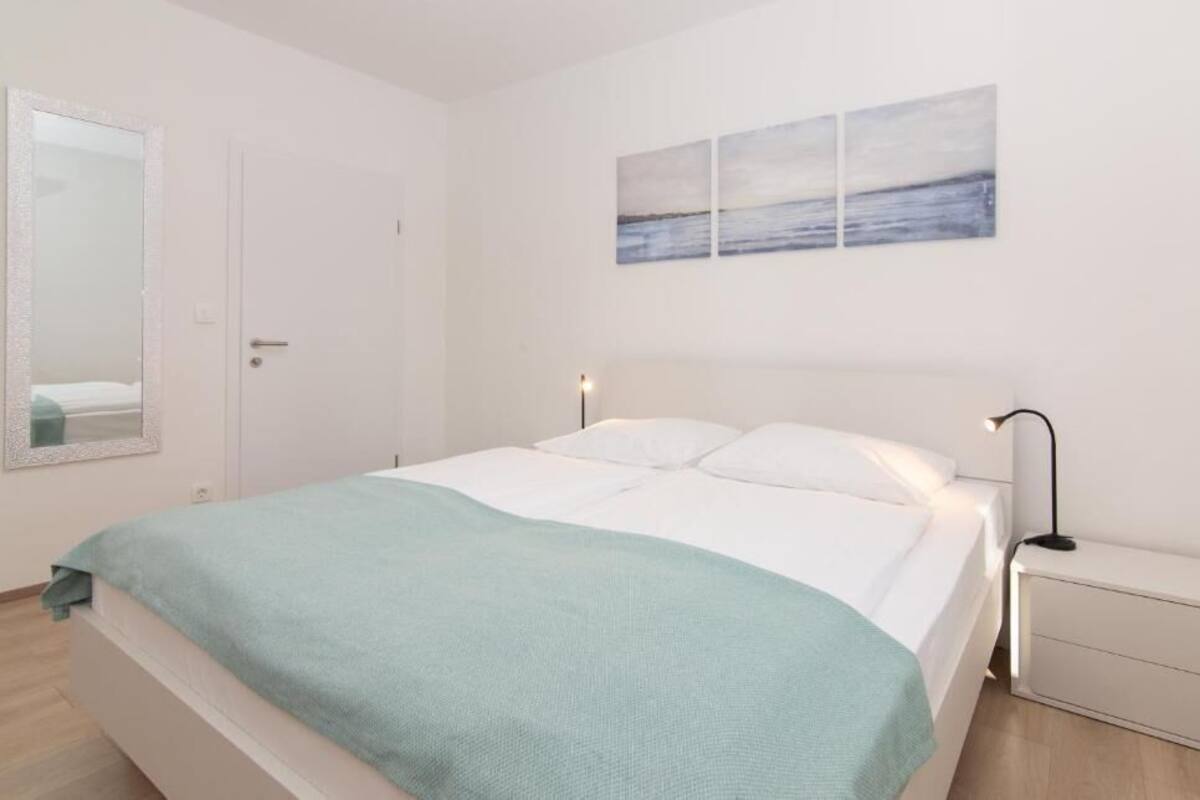 Ein Schlafzimmer mit einem Bett, Nachttischen, einem Spiegel und einem an der Wand befestigten Kunstwerk.