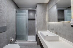 A modern bathroom with a glass shower enclosure, a white sink, and a toilet. - Prime Suites Apart Hotel and Residence (Istanbul)