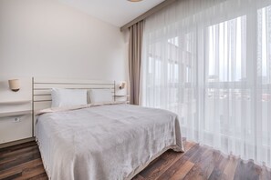 A bedroom with a bed, a nightstand, a wall-mounted lamp, and sheer curtains over a window. - Prime Suites Apart Hotel and Residence (Istanbul)
