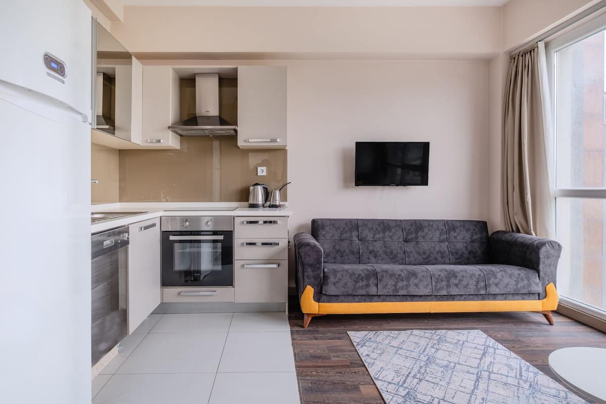 A modern kitchen with a built-in oven, a coffee maker, and a TV mounted on the wall.