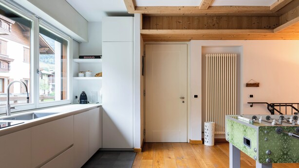 Een moderne keuken met witte kasten, een raam en een houten plafond.