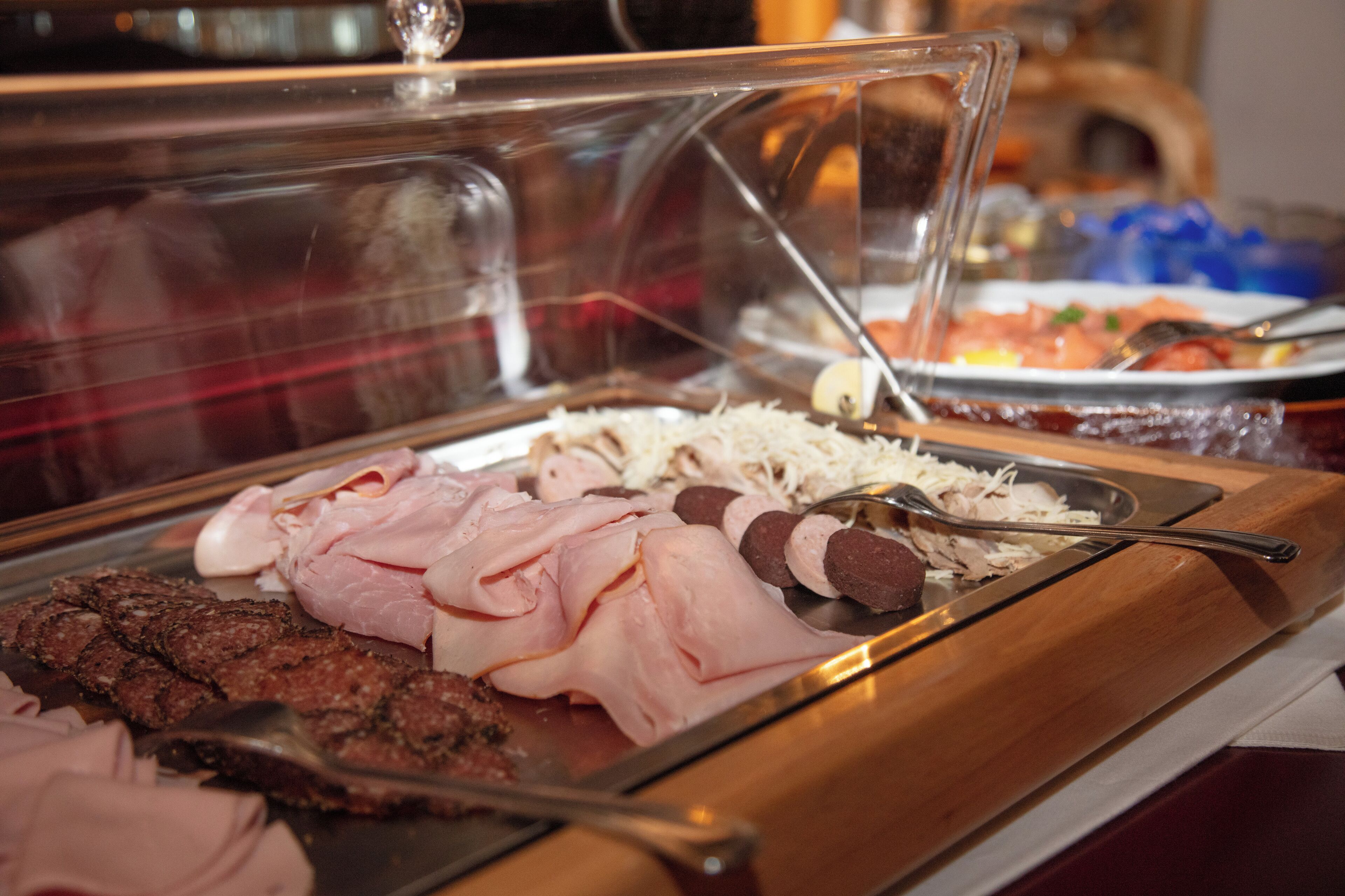 Un buffet proposant différentes sortes de viandes et une vitrine réfrigérée.