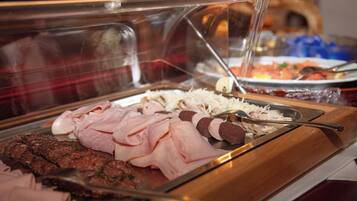 Un buffet proposant différentes sortes de viandes et une vitrine réfrigérée.