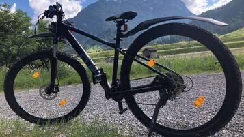 Una bicicleta de montaña estacionada en un camino de grava con una vista panorámica de la montaña al fondo.