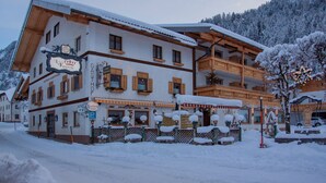 Ein traditionelles Gebäude im alpinen Stil mit schneebedecktem Dach und Holzbalkonen.