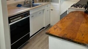 A kitchen with white cabinets, a wooden countertop, a window, and a gas stove. - The Kennywood Suite - The Blue Racer Car (Duquesne)