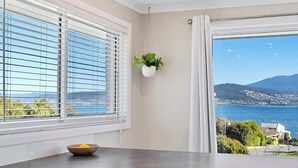 A room with a large window, a hanging plant, and a bowl on the table.
