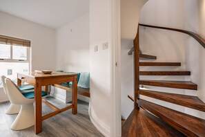 Et moderne interiør med et træspisebord, en sofa og en spiraltrappe.