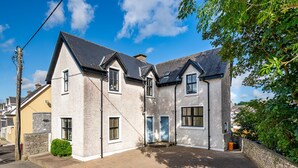 A two-story house with a stone facade, multiple windows, and a paved driveway. - One Bedroom Apartment to Sleep 2 in the Heart of Kenmare Town (Kenmare)