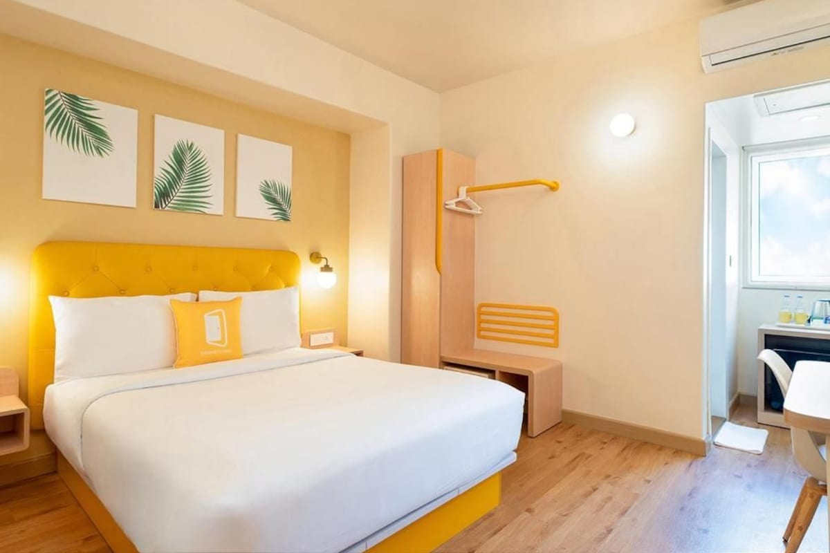 A hotel room with a bed, a desk, a shower, and a window.