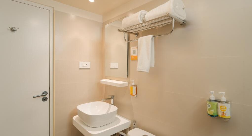 A bathroom with a white sink, a towel rack, and two bottles of hand soap.