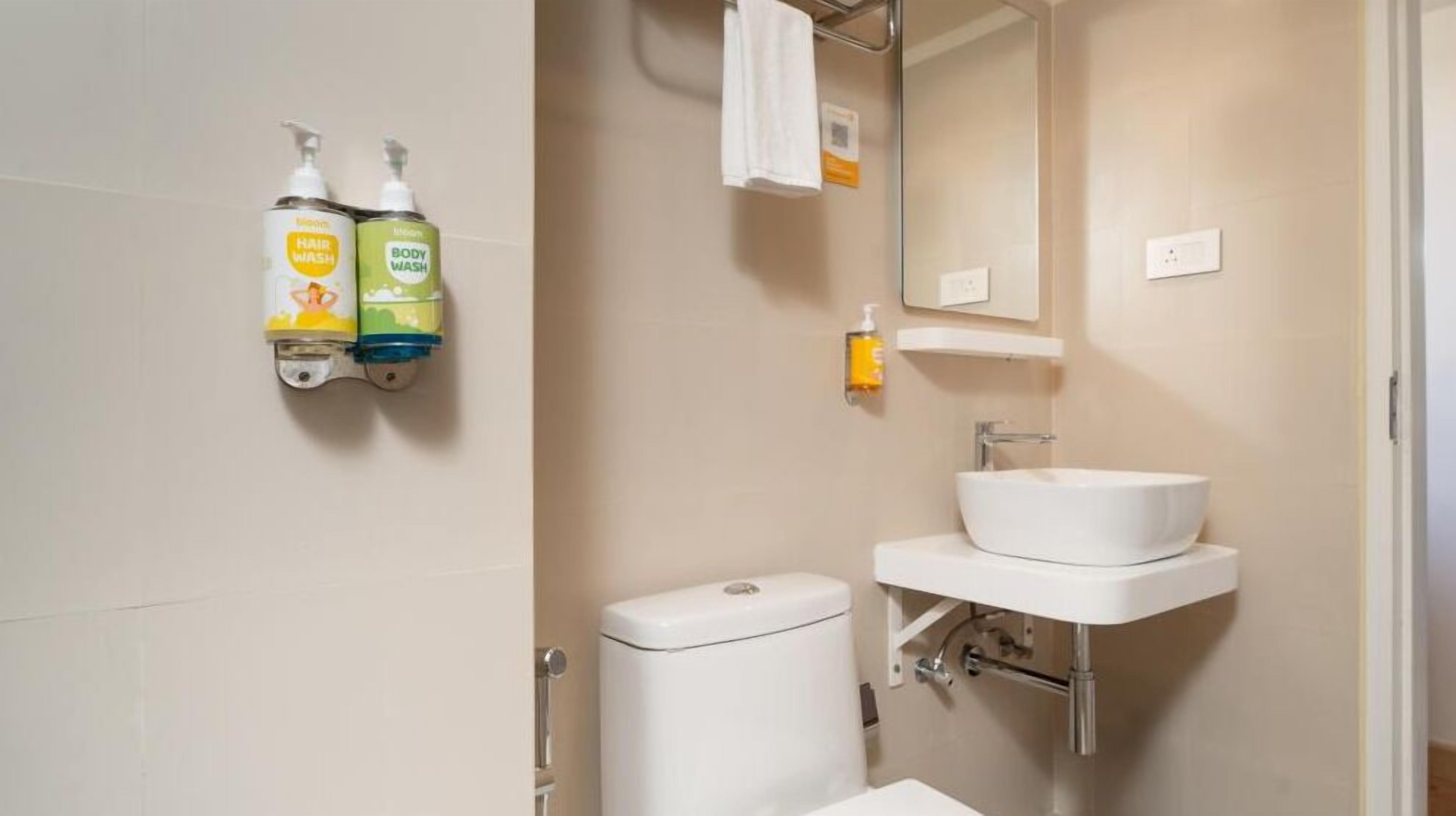Une salle de bain avec un lavabo blanc, des toilettes et deux distributeurs de savon fixés au mur.