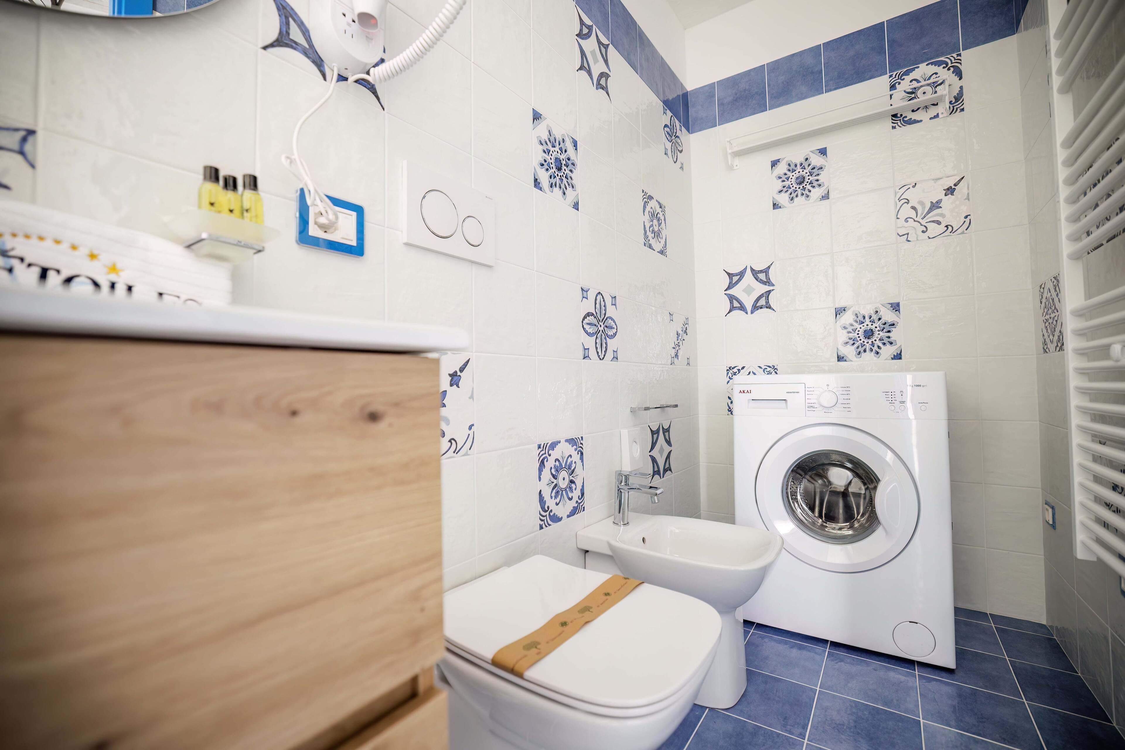 Un baño equipado con lavadora, inodoro y lavabo.